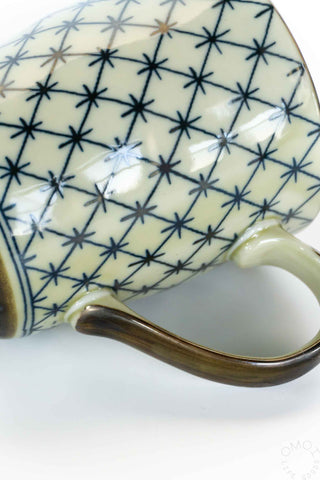 Ceramic cup with blue geometric pattern on a white background