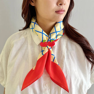 Person wearing a colorful scarf with red accents on a plain background