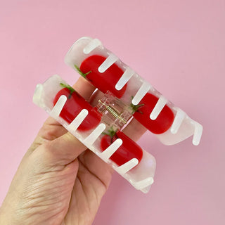 Hold holding open claw clip with tomato design to demonstrate usage