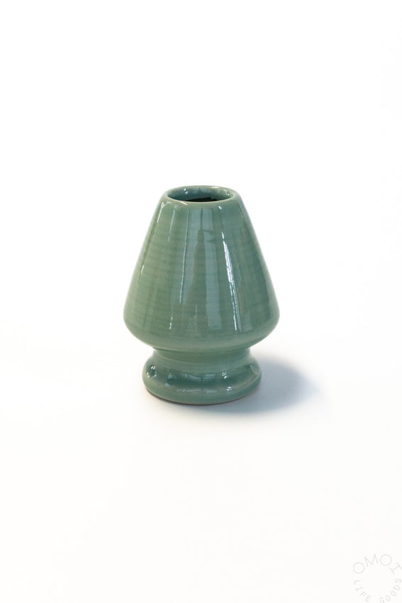 Green ceramic whisk stand on a white background