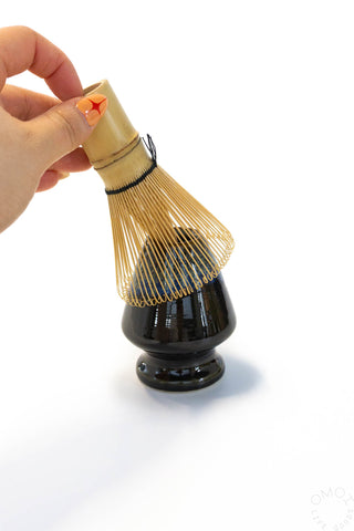 Traditional Japanese tea whisk held by a hand on a white background