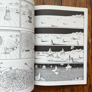 Open book with black and white illustrations on a wooden surface