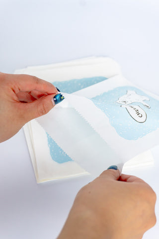 Two hands opening a flat bag with a polar bear design on a white background