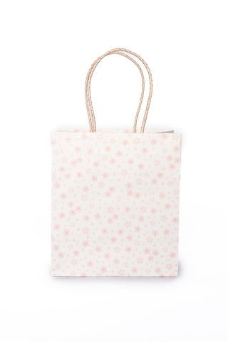 White gift bag with pink floral design with handles on a white background