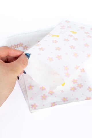 Hand opening a white bag with floral patterns on a white background