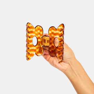 Person holding open honey checkered hair clip