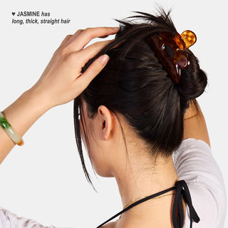 Person with long, thick, straight hair up in a honey checkered hair clip