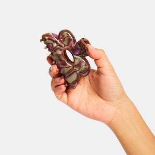 Hand holding a decorative hair clip against a plain background