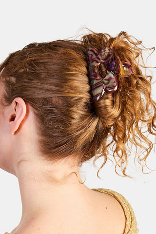 Woman with curly hair wearing a decorative hair clip against a white background
