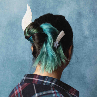 person with black and blue hair wearing star shaped hair clip against a blue backdrop