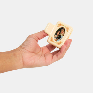 Hair clip with photo frame held in hand against a white background