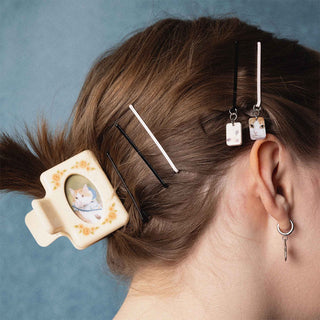 Person with decorative hair clips and pins in their hair against a blue background