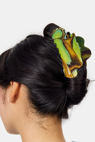 Person with a green and brown claw hair clip in their hair on a white background