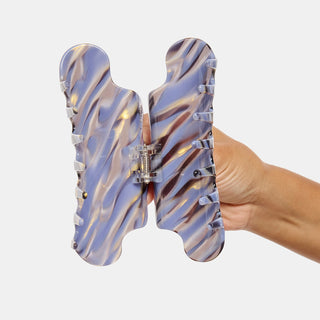 Hand holding a colorful claw hair clip against a white background