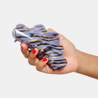Hand holding a claw hair clip with a marble pattern on a white background