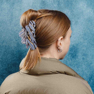 Person with hair up with a colorful hairclip against a textured blue background