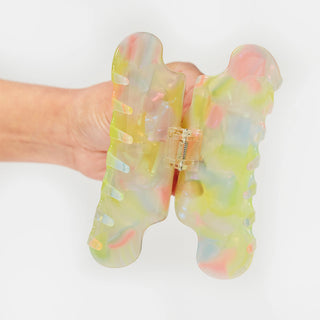 Pastel translucent claw clip on hand, open hinge with gold-toned hardware