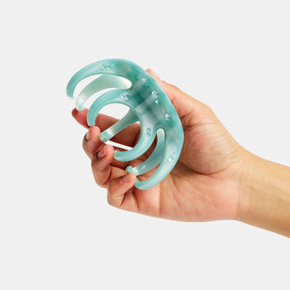 Hand holding a light blue hair clip against a white background