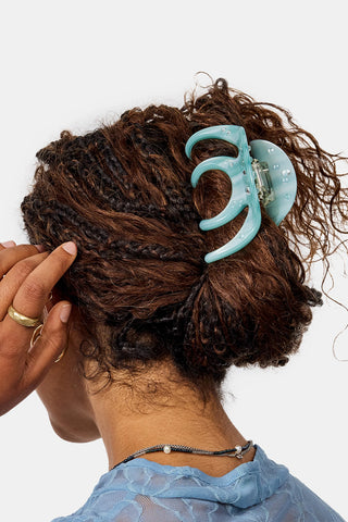Person using a light blue hair clip on a white background