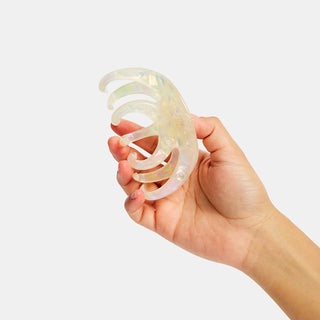 Hand holding a clear, octopus claw clip against a white background