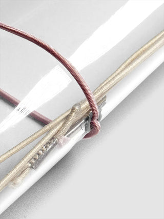 Close-up of red and beige elastic bands on silver-ring travel cover