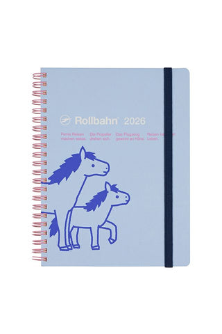Blue notebook with horse illustrations and 'Rollbahn 2026' branding and pink details on a white background