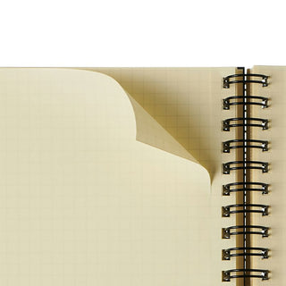 Close-up of a spiral-bound notebook with beige cover showing page perforation