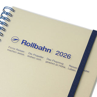 Beige notebook with 'Rollbahn' branding and navy details on a white background