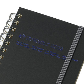 Black notebook with spiral binding and embossed text that reads "Rollbahn 2026" on a white background