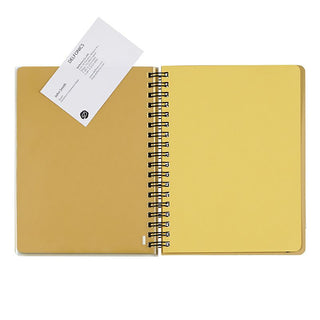 Open yellow notebook pages with a spiral binding on a white background. The plastic insert pages are holding a business card