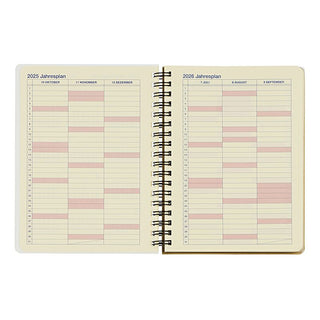 Open spiral-bound planner with 2025 and 2026 monthly pages on beige paper.
