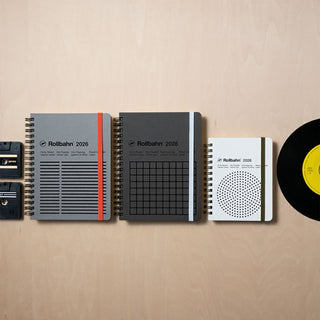 Three notebooks with different designs on a beige background, accompanied by a vinyl record.