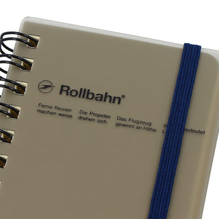 Notebook with 'Rollbahn' branding and a blue strap on a white background