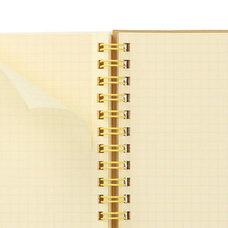 Close-up of a beige notebook with yellow spiral binding