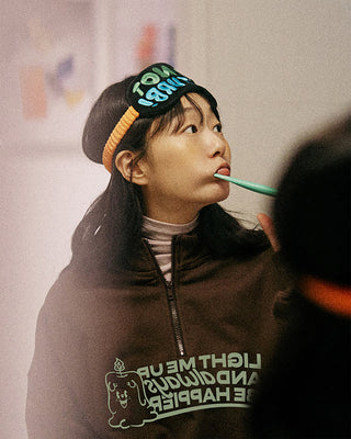 Person wearing a hoodie with text and graphics, brushing their teeth.