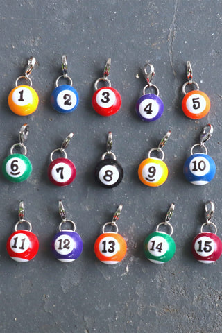 Set of 15 colorful pool ball number charms on a gray surface
