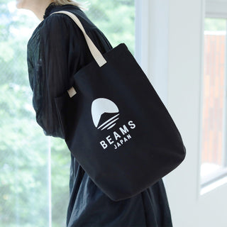 Person holding a tote bag with 'Beams Japan' logo in a bright room.
