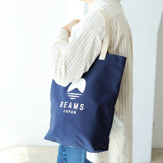 Person holding a blue tote bag with 'BEAMS JAPAN' logo