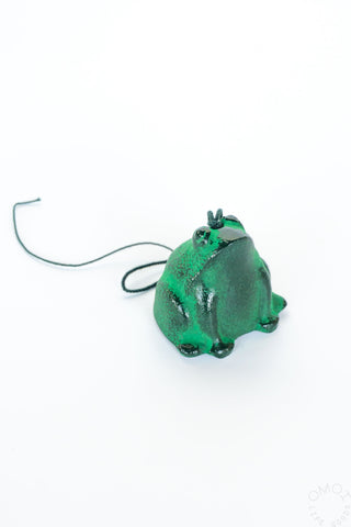 Green frog-shaped wind chime with a string on a white background