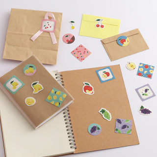 Notebooks and envelopes with decorative fruit stickers on a white background