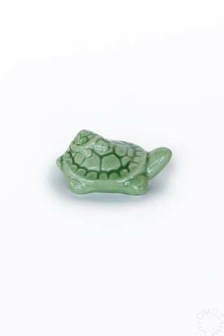 Green ceramic turtle with a smaller turtle on its back on a white background