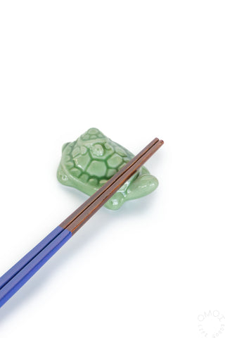 Green turtle-shaped chopstick rest with pair of chopsticks on a white background