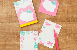 Set of memo pad sheets with cat designs on a wooden surface