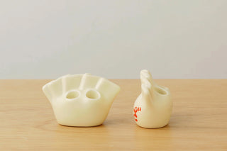 Two white porcelain pen holders on a wooden surface