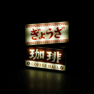 Two illuminated keychain signs with Japanese text, one says 'Coffee Hall'