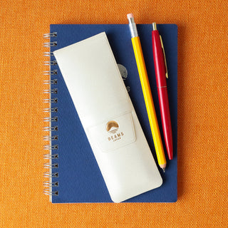 Blue notebook with a white pen holder, red pen, and yellow pencil on an orange background