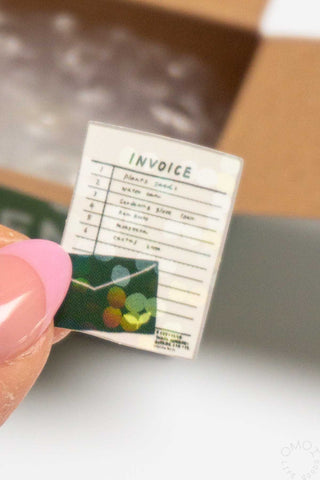 Small invoice sticker held by a hand with a blurred background