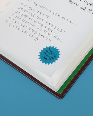 Open book with handwritten text next to a sticker on a blue background