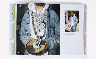 Book open to a page with a person wearing a denim jacket and white hoodie, holding a round object.