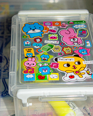 Clear plastic container with colorful cartoon stickers on a blurred background